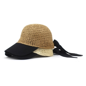 Detail of woven straw sun hat with dual-layer brim and decorative black silk bow