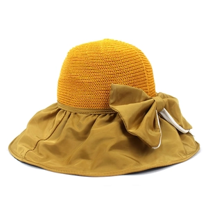 Detail of straw sun hat featuring yellow woven top and large bow with white stripe accents