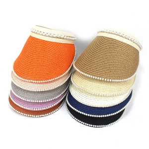 Detail of wide brim straw sun hats showing pearl trim in various vibrant colors