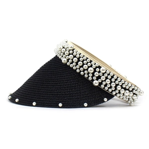 Close-up of black straw sun visor featuring elegant white pearl embellishments and texture