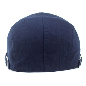 Detail of navy cotton flat cap with side metal buckles and fine stitching texture
