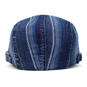 Detail of adjustable metal buckle and striped denim texture on the blue flat cap