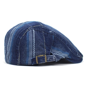Detail of vintage blue denim flat cap with striped patchwork and adjustable metal side buckle