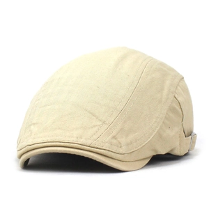 Detailed close-up of light khaki flat cap showing metal buckle and herringbone texture
