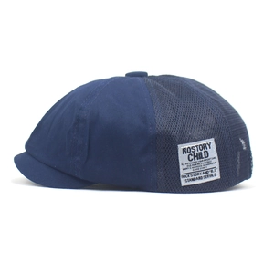 Detail of navy newsboy cap showing breathable mesh panels and vintage woven label