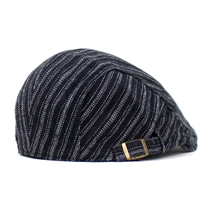 Détail de la casquette plate vintage en denim avec rayures blanches et boucle dorée réglable