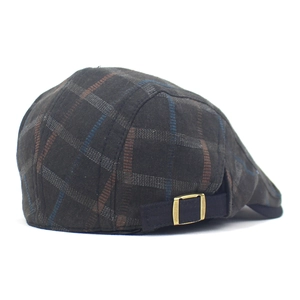 Detail view of adjustable metal buckle and plaid fabric on retro newsboy cap