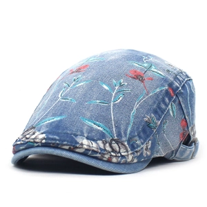 Detail van bedrukte denim baret met bloemmotieven en verstelbare metalen gesp aan de zijkant