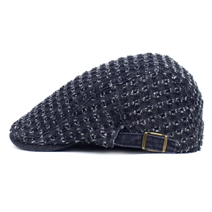 Close-up of vintage blue denim flat cap with woven texture and adjustable metal buckle