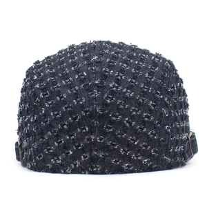 Detail of distressed denim beret with ripped texture and adjustable copper side buckles