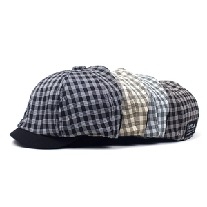 Detail view of plaid newsboy caps in various colors with stylish letter labels