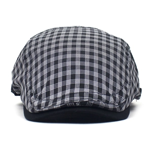 Detailed close-up of a vintage black and white plaid flat cap with a solid black brim