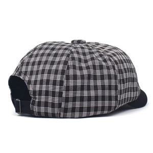 Detailed close-up of the black and white plaid newsboy cap with an adjustable metal buckle