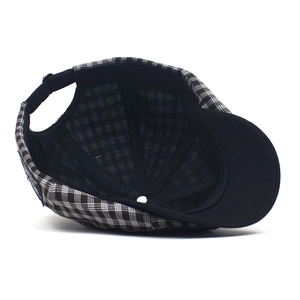 Detail view of plaid beret interior with black lining and adjustable back buckle strap