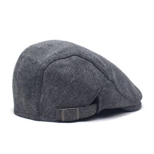 Detailed close-up of dark gray knit flat cap featuring an adjustable metal side buckle