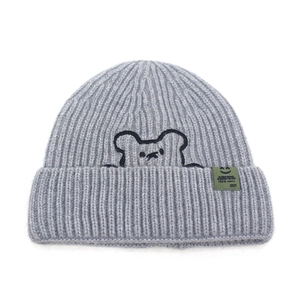 Detail of grey beanie showing ribbed knit texture with bear embroidery and green label