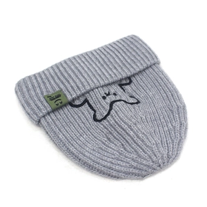 Detail of light grey knit beanie featuring a small cartoon dog embroidery and green tag