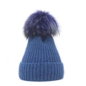 Detailed close-up of dark blue knit winter hat with a large fluffy purple pom-pom