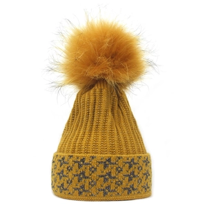 Dettaglio del berretto in maglia giallo zenzero con pompon e stelle argentate glitter