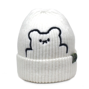 Close-up of white knit beanie with bear embroidery and detailed woven tag