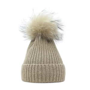 Detailed close-up of khaki ribbed knit beanie with a fluffy faux fur pompom detail