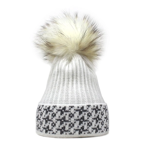 Dettaglio del berretto in maglia bianca con pompon soffice e fili argentati brillanti