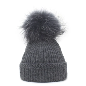 Detailed close-up of dark grey ribbed knit beanie with a fluffy faux fur pompom decoration