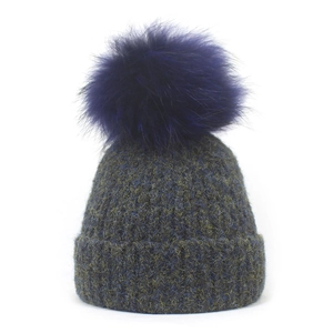 Detail of winter knit beanie showing mixed gray-blue texture and purple pompom
