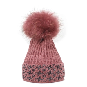 Berretto in maglia rosa cipria da donna con un grande pompon di pelliccia sintetica