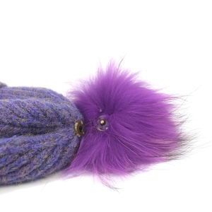 Detail showing the metal snap button for the detachable purple faux fur pom-pom on beanie