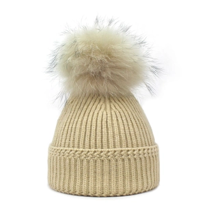 Women's rib-knit beanie hat in beige featuring a large fluffy faux fur pom-pom on top