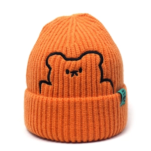 Detail of orange knitted beanie featuring bear embroidery and mint green side label