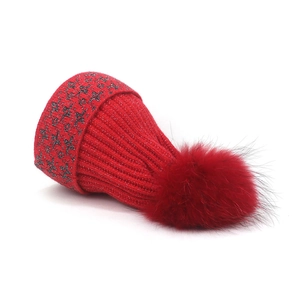 Dettaglio del cappello in maglia rossa con pompon e stelle argentate luccicanti