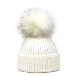 White winter knit beanie hat with large fluffy faux fur pompom on white background