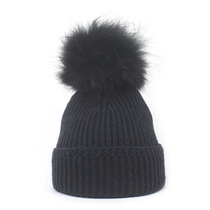 Detail of black ribbed knit beanie with soft faux fur pompom for winter warmth