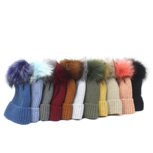 Chunky knit beanies for women with large pom-poms shown in eleven vibrant color options