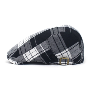 Close-up of black and white plaid beret featuring a vintage copper metal side buckle