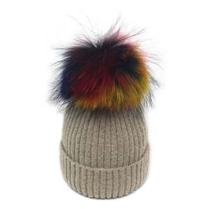Détail du bonnet en maille gris avoine avec un pompon en fausse fourrure multicolore vif