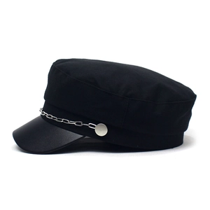 Detail of black baker boy hat featuring a faux leather visor and silver chain accent