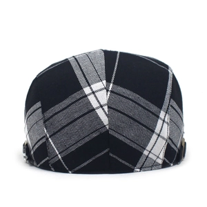 Detailed view of black and white plaid beret cap with metal side adjustment buckle