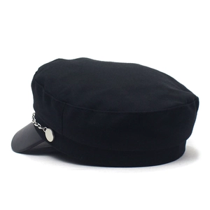 Detail of black newsboy cap with leather brim and side silver chain with metal buckle