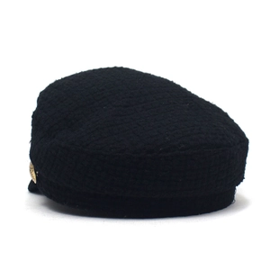 Dettaglio di un cappello da marinaio nero in tweed con bottone decorativo dorato laterale