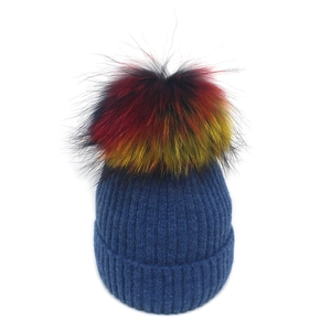 Détail du bonnet en maille bleu marine avec pompon coloré en fausse fourrure