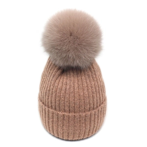 Close-up of ribbed knit texture and large fluffy faux fur pompom on winter beanie