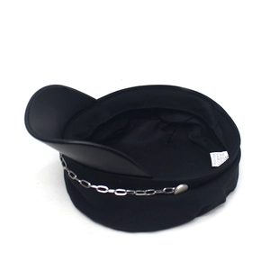 Detail view of black newsboy hat featuring metal chain and inner lining with fabric label