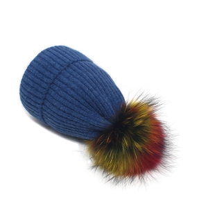 Détail du bonnet en maille bleu marine avec un grand pompon en fourrure tricolore