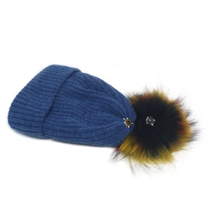Détail du bonnet en maille bleu marine avec pompon coloré et bouton pression en métal