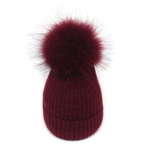 Detailed macro view of the wine red ribbed knit beanie featuring a large fluffy faux fur pompom