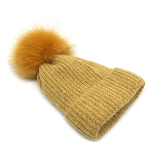 Detailed close-up of ginger yellow ribbed knit beanie with a fluffy oversized faux fur pompom