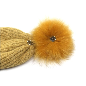 Detail of detachable fluffy faux fur pompom with metal snap button on ginger knit beanie